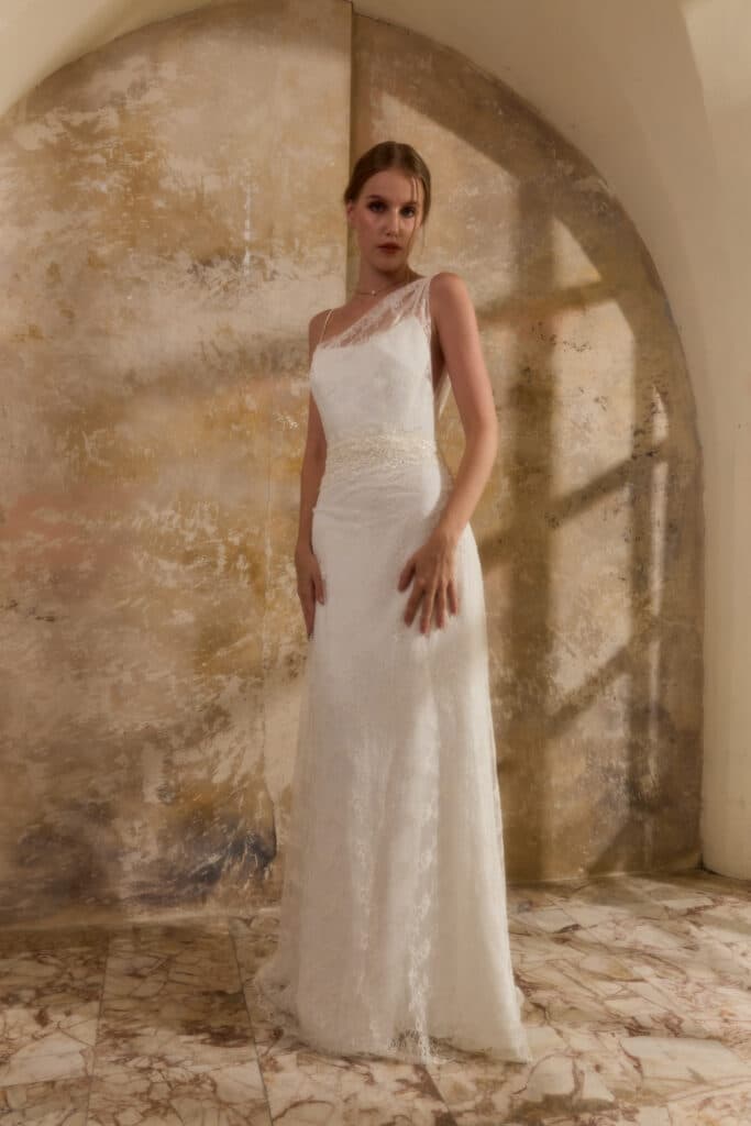 femme dans une robe de mariée fourreau et asymétrique tout en dentelle